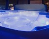 Jacuzzi z niebieskim oświetleniem we wnętrzu z widokiem na nocne miasto.