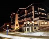 Hotel Monzoni nocą z ozdobami świątecznymi i zaśnieżoną okolicą.