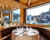 Luksusowa restauracja z widokiem na zaśnieżony krajobraz i górską wioskę.