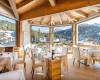 Restauracja z nakrytymi stołami i widokiem na ośnieżone góry.