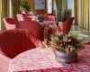 Restauracja z czerwonymi obrusami i aranżacjami kwiatowymi na stołach.