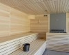 Wnętrze nowoczesnej sauny z drewnianymi ławami i metalowym wiadrem.
