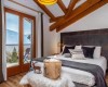Sypialnia z łóżkiem małżeńskim, widokiem na góry, drewnianymi belkami i nowoczesnym wystrojem.