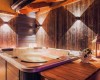 Wewnętrzne jacuzzi otoczone drewnianymi panelami z oświetleniem i lampionem na stole.
