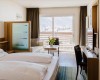 Nowoczesny pokój hotelowy z podwójnym łóżkiem, balkonem i widokiem na góry.