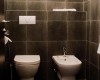 Toaleta i bidet w ciemnej łazience z kafelkami.