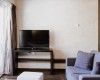 Nowoczesny salon z telewizorem na stole, sofą i dużym oknem.