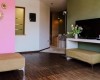 Salon z różową i zieloną ścianą, telewizorem i kwiatami w wazonie.