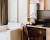 Nowoczesny pokój hotelowy z telewizorem, biurkiem i sofą.