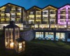 Nowoczesny hotel z podświetlonymi fasadami i latarniami w ogrodzie o zmierzchu.