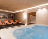 Strefa wellness z jacuzzi i pomarańczowymi leżakami.
