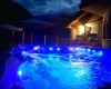 Jacuzzi z niebieskim oświetleniem w nocy obok domu.
