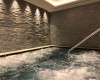 Wewnętrzne jacuzzi z kamienną ścianą i schodami.