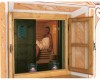 Kobieta siedząca w saunie, widok przez drewniane okno.