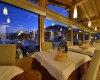 Wnętrze restauracji z nakrytymi stołami i panoramicznymi oknami o zmierzchu.