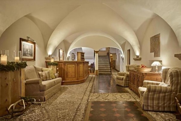 Eleganckie lobby z sklepionymi sufitami, drewnianymi elementami i wygodnymi fotelami.