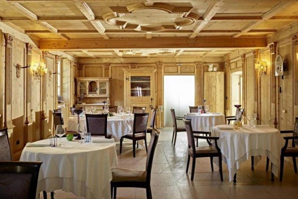 Stylowa restauracja z drewnianymi panelami i okrągłymi stołami.