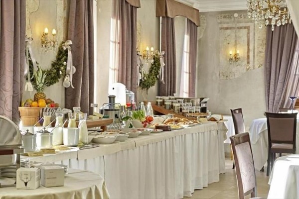 Stół bufetowy z jedzeniem w eleganckiej restauracji z kryształowymi żyrandolami i dekoracjami na ścianach.