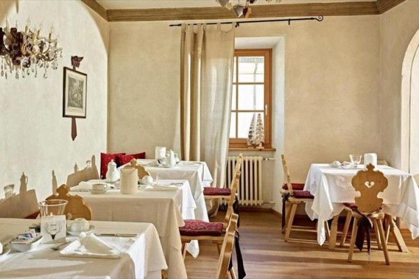 Elegancka restauracja z drewnianym sufitem i białymi obrusami na stołach.