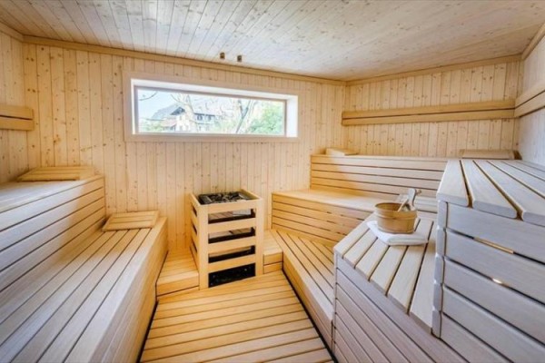 Drewniana sauna z ławkami i oknem.