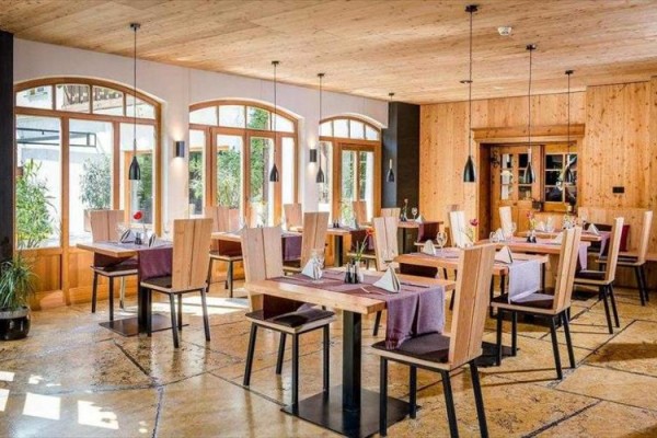 Restauracja z drewnianymi meblami i dużymi oknami.
