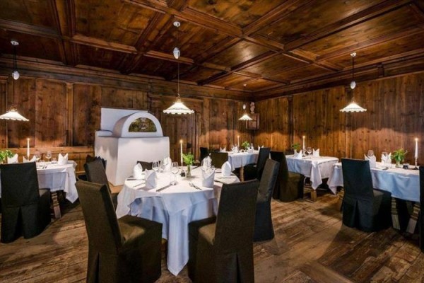 Luksusowa restauracja z drewnianą okładziną i okrągłymi stołami z białymi obrusami.