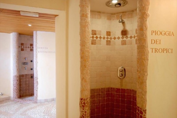 Spa prysznice z ceramicznymi płytkami i napisami na ścianie.