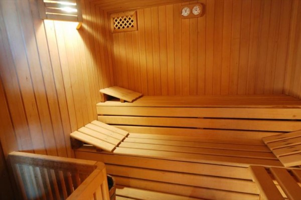 Drewniana sauna z ławkami i miernikami na ścianie.