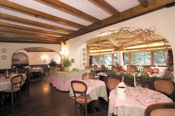 Restauracja z drewnianym sufitem, nakrytymi stołami i różowymi dekoracjami.