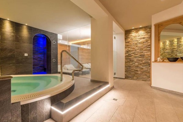 Nowoczesne centrum wellness z jacuzzi i kamiennymi ścianami.