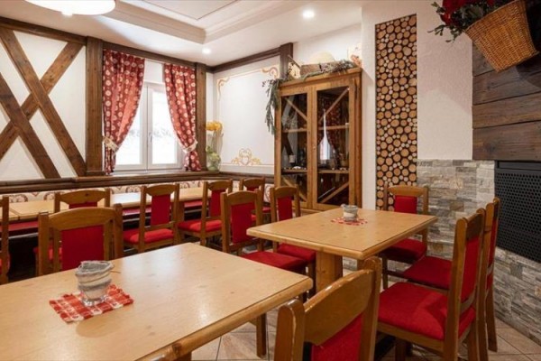 Rustykalny wystrój restauracji z drewnianymi meblami i czerwonymi dodatkami.