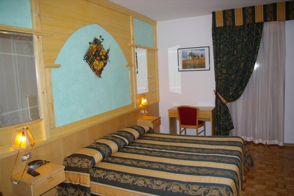 Pokój hotelowy z łóżkiem małżeńskim, biurkiem i dekoracjami na ścianie.
