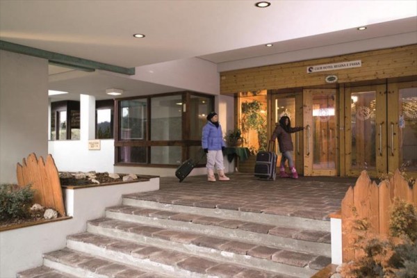 Dwie osoby z walizkami przed wejściem do hotelu.