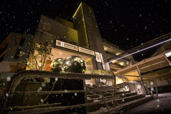 Nocny widok na oświetlony hotel z padającym śniegiem.
