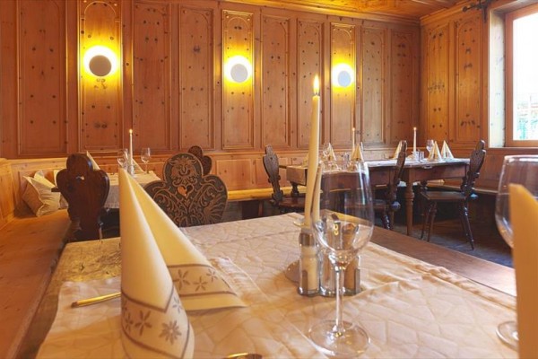 Restauracja z drewnianym wykończeniem, nakrytymi stołami i zapalonymi świecami.