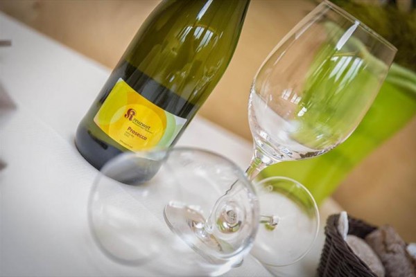 Butelka prosecco obok dwóch pustych kieliszków na stole.