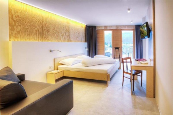 Nowoczesny pokój hotelowy z drewnianymi meblami, łóżkiem i balkonem.