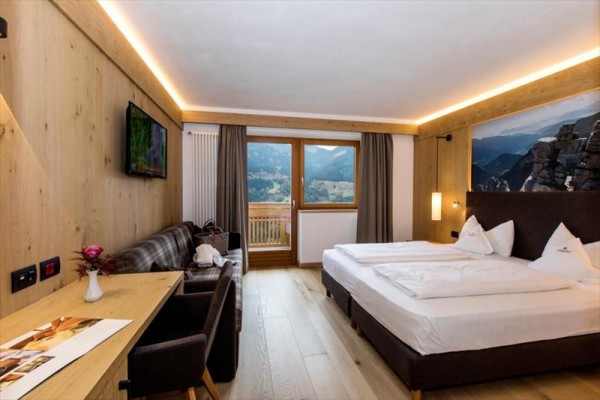 Nowoczesny pokój hotelowy z podwójnym łóżkiem, sofą i widokiem na góry.