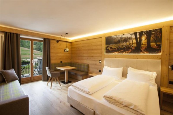 Nowoczesny pokój hotelowy z drewnianą boazerią, łóżkiem małżeńskim i balkonem.