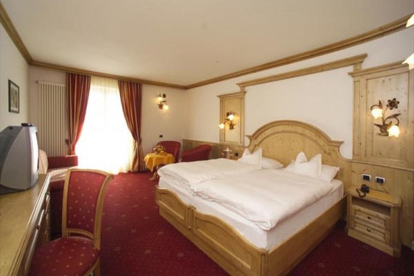 Zewnętrzny taras hotelowy z metalowymi stołami i krzesłami, kwiatami i parasolami.