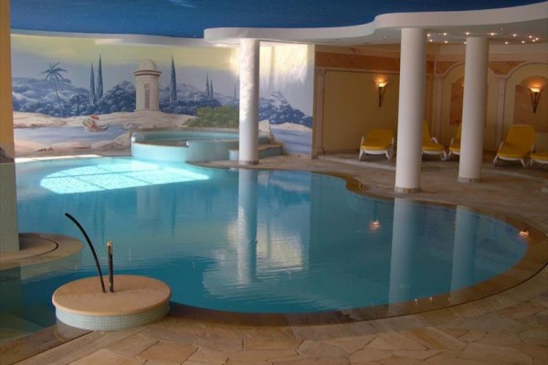 Hotel otoczony zielenią, z górami w tle.  