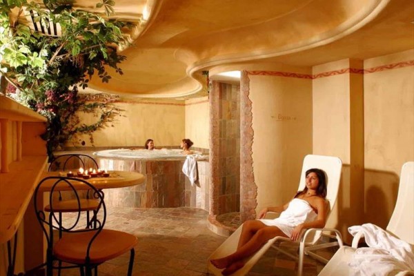 Luksusowa strefa wellness z jacuzzi i leżakami do relaksu, ozdobiona roślinami i świecami.