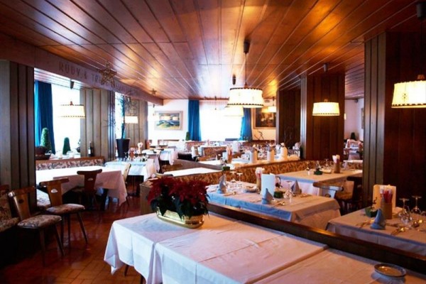 Restauracja z drewnianym wykończeniem i nakrytymi stołami.