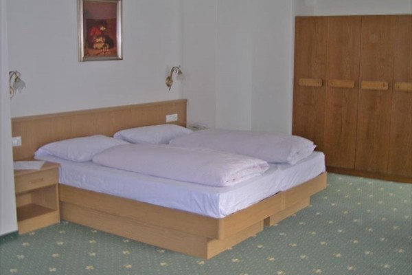 Łóżko małżeńskie w pokoju hotelowym z drewnianą szafą i obrazem na ścianie.