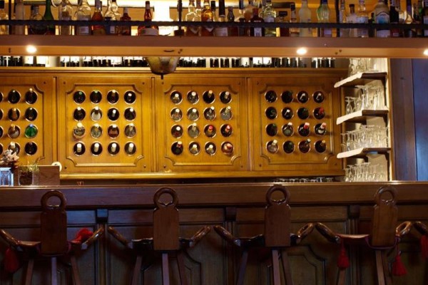 Drewniany bar z półkami pełnymi butelek alkoholu i kieliszkami do wina.