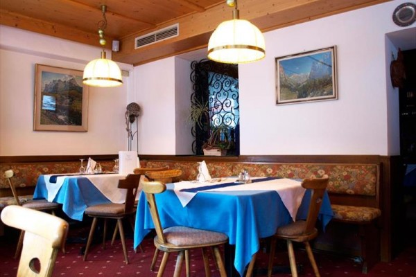 Restauracja z drewnianymi meblami i niebieskimi obrusami na stołach.