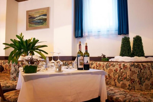 Stół w restauracji z kwiatem, winami i nakryciem.