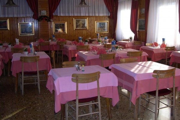 Restauracja z drewnianymi stołami pokrytymi różowymi obrusami i obrazami na ścianach.