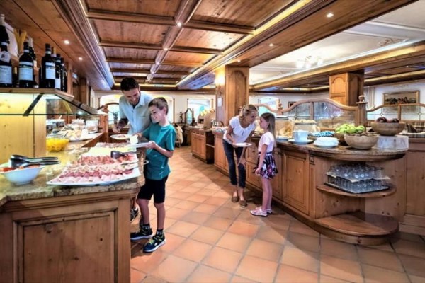 Ludzie wybierają jedzenie z bufetu w restauracji z drewnianymi elementami.
