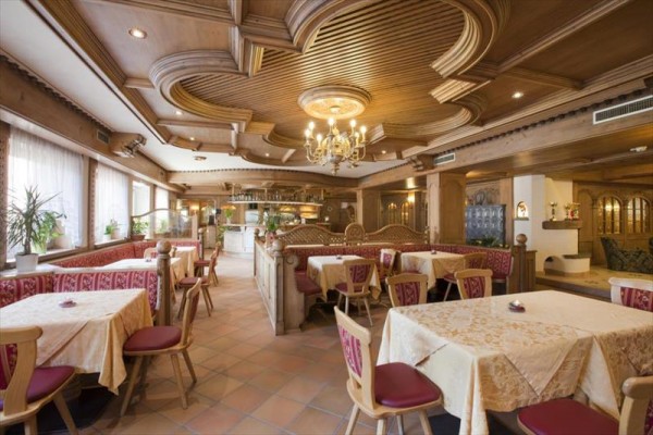 Tradycyjna restauracja z drewnianym wnętrzem i materiałowymi obrusami na stołach.